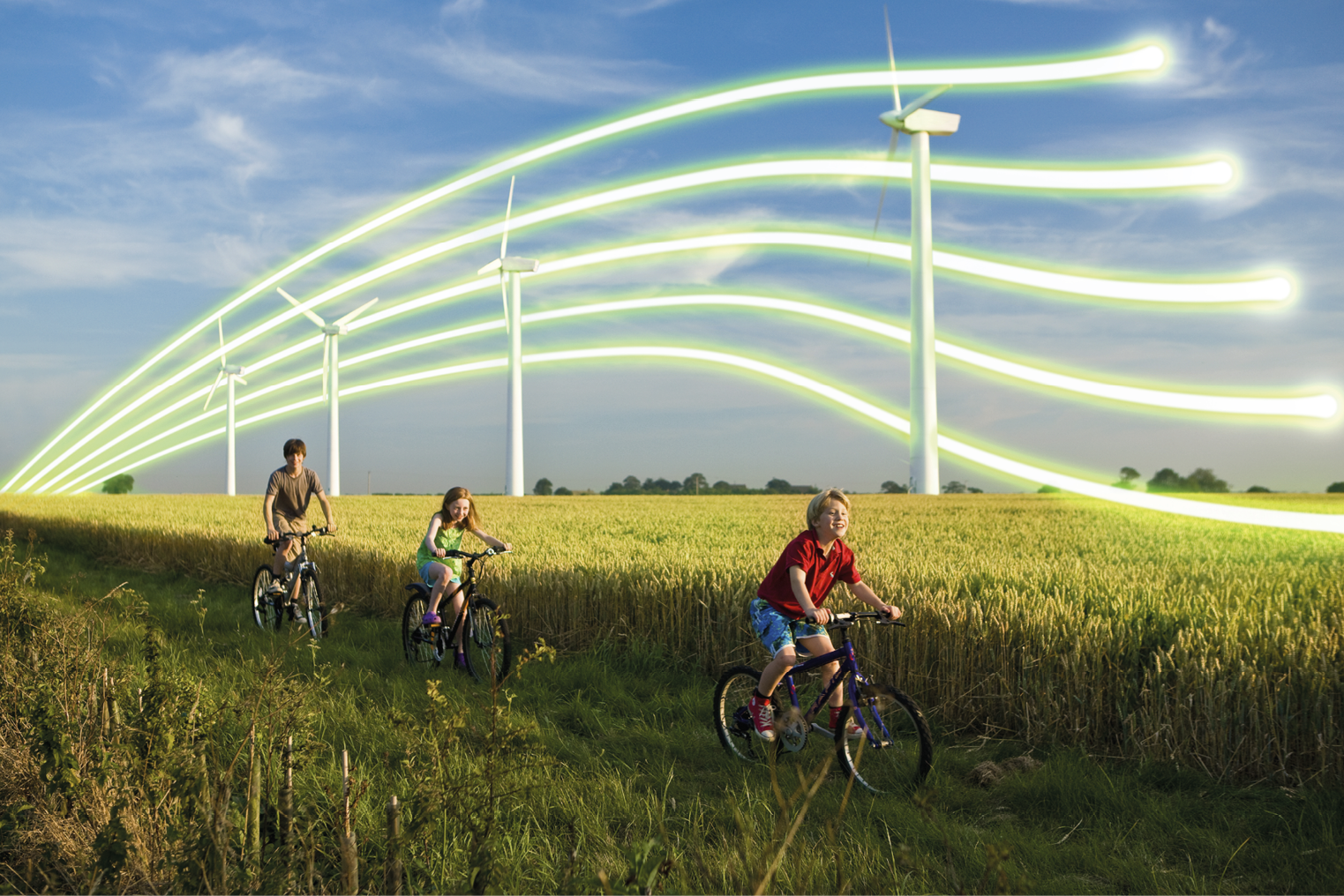 3 children on bicycles in front of wind turbines in a wheat field.
